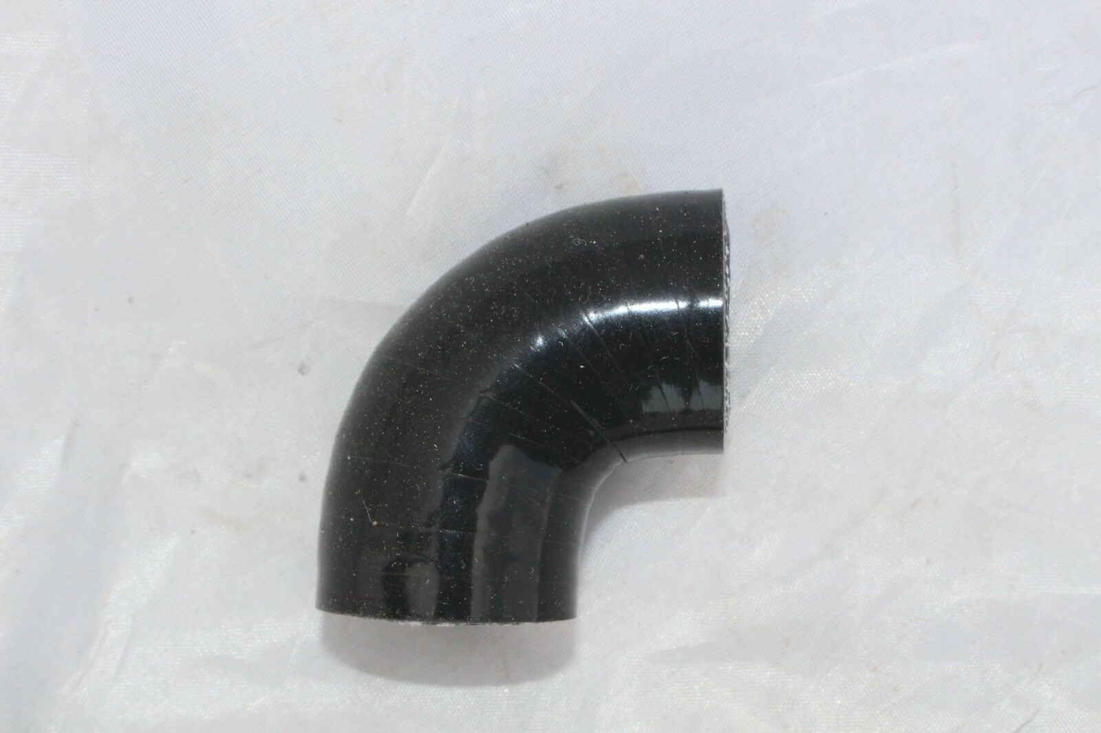 A black pipe sitting on top of a white sheet.